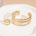 Dettaglio ravvicinato di bracciale foglia d'oro testurizzato e anello coordinato su vassoio - Tre strati dorati (set da due pezzi)