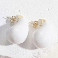 Macro shot of minimalist white enamel teardrop earrings on natural stone texture - White