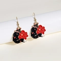 Detail of red and black fox motif earrings with golden frames and enamel flower details - Black Red Fox Peony