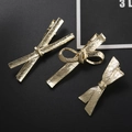 Tres elegantes pinzas para el cabello con lazo metálico dorado sobre fondo negro - Set de tres piezas