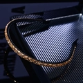 Close-up of sparkling champagne gold crystals on a slim black metal headband - Tawny Glass