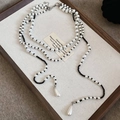 Macro detail of a vintage double-layered pearl necklace with black faceted beads on linen - Black Beaded Style / White/Black