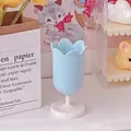 Detail view of light blue tulip storage pot with white round base on desk setup - Blue