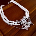 Detailed macro shot of a double-layer pearl necklace featuring silver diamond butterfly charms - Cool White Pearl/Silver Butterfly