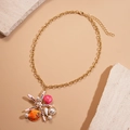 Collana dorata con stella marina, conchiglia, perle e strass su sfondo beige - Collana-Rosa