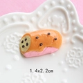 Detailed macro view of an orange and pink resin eclairs charm on a white relief plate - European Bread Slice