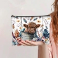 Detail of Highland Cow print on large capacity canvas makeup bag held by hand - Highland Cow with Flowers & Feathers (jiayingpbb093)