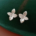 Nahaufnahme von Blumenohrringen mit Zirkonia-Pavé-Blütenblatt auf grünem Samtgrund - Silber (Silberstift)