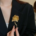 Detail view of a vintage gold rose brooch pinned on a black suit lapel with matte finish - Gold Realistic Rose