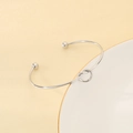 Brazalete minimalista plateado de acero inoxidable en forma de C con un diseño de nudo central - Color Acero (KB207034-Z)