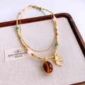 Détail d'un collier hirondelle vintage doré avec perles sur un plateau à bijoux - Or
