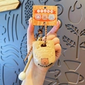 Beige Capybara sleutelhanger met kralenkoord en oranje merkverpakking op de achtergrond - Capibara Stijl