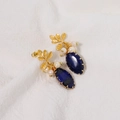 Elegant gold earrings with white pearls and blue lapis lazuli stones on white fabric - Oval Lapis Lazuli Style