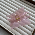 Détail de la pince à cheveux papillon rose translucide avec ressort doré sur plateau - Rose Gelée