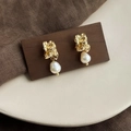 Detail of baroque pearl earrings with textured gold metal stud on vintage wooden base - Style 17