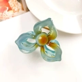Detailed top view of a hollow plumeria hair claw clip with blue and amber resin marbling - 3-Petal Clover Foggy Blue