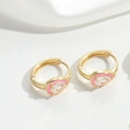 Close-up of gold earrings featuring pink enamel and a teardrop clear gemstone on silk - Pink