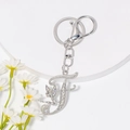Makro-Detail von silbernem Schlüsselanhänger Buchstabe F mit Strass und kleiner Fee - Stil F / Silber