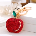Close-up of red rhinestone apple keychain with gold metal plating and green leaf detail - Red Rhinestone Apple