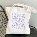 Weiße Canvas-Einkaufstasche mit lila und blauen Kosmos-Blumen auf schwarzem Stuhl - Blau-Violetter Kosmos