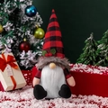 Gnomo de Navidad nórdico con gorro de cuadros rojos y barba blanca en fondo nevado - Gnomo sentado sin rostro (sombrero a cuadros)