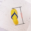 Detail shot of 43mm yellow acrylic flip-flop pendant with silver glitter on stone surface - Yellow Flip-flops
