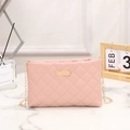Pink quilted crossbody bag with gold chain strap and metal plate on marble surface - Pink