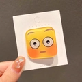 Fermaglio per capelli giallo con emoji a goccia su scheda espositiva in mano - Faccia Quadrata Imbarazzata