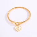 Golden twisted bangle with white enamel heart charm featuring letter Q in the center - Letter Q