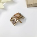 Detail view of U-shaped marble acetate hair hook with gold metal base on white background - Rainbow