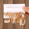 Gold-tone earrings set with artificial pearls and butterfly pendants on dark wood - 28 KC Gold