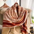 Detailed view of silk scarf with red Toile de Jouy print draped on a trench coat - Orange