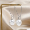 Dettaglio di eleganti perle bianche su ganci a U in argento appesi a un supporto dorato - Perla Bianca/Gancio Argentato Lungo