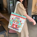 White canvas tote bag with colorful cartoon dragon print worn by a model in a cafe - Little Dragon Man