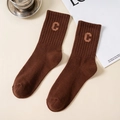 Kaffeebraune gerippte Crew-Socken mit besticktem Buchstaben C auf winterlichem Hintergrund - Kaffeebraun