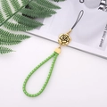 Detail view of a green braided phone lanyard with a gold rose flower pendant accessory - Green