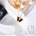 Detailed close-up of a golden butterfly necklace with black enamel and zircons on silk - Black