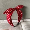Rotes Haarband mit weißen Punkten und Schleife, präsentiert auf einem Buch - Burgunderrot