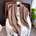 Close-up of brown linen shawl draped on a white shirt showing soft texture and drape - Camel