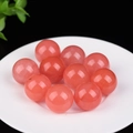 Polished round red cat eye stone beads displayed on a white plate with black background - Watermelon red