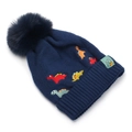 Detail of navy knit winter hat featuring colorful dinosaur embroidery and a faux fur pom-pom - 2-6 Years Old / Navy Blue
