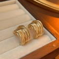Detailed close-up of golden spiral texture C-shaped hoop earrings in a premium jewelry box - Gold