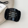 Close-up of black acetate hair claw clip with cutout design on ceramic plate - Small Black