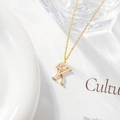 Detail of gold letter K necklace with zircon pendant on a white ceramic plate - Letter K