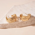 Nahaufnahme goldener C-förmiger Ohrringe mit strukturierter Metalloberfläche auf weißem Stein - Stil mit Silber-Ohrstecker / Gold