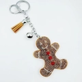 Close-up of rhinestone gingerbread man keychain with brown tassel and small silver bell - Gingerbread Man