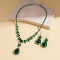Dettaglio della collana e orecchini con pietre verdi a goccia su superficie in pietra - Set Collana Verde (2 Pezzi)
