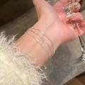 Elegant triple-layer silver snake chain bracelet shown on woman wrist in luxury setting - Silver Three Layer Fine Snake (MY35415)