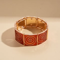 Makro-Detail eines roten Emaille-Stretch-Armbands mit goldenen Spiralen im Retro-Stil - Rot