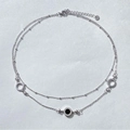 Macro detail of silver double-layer necklace with black Roman numeral hollow pendants - Steel
